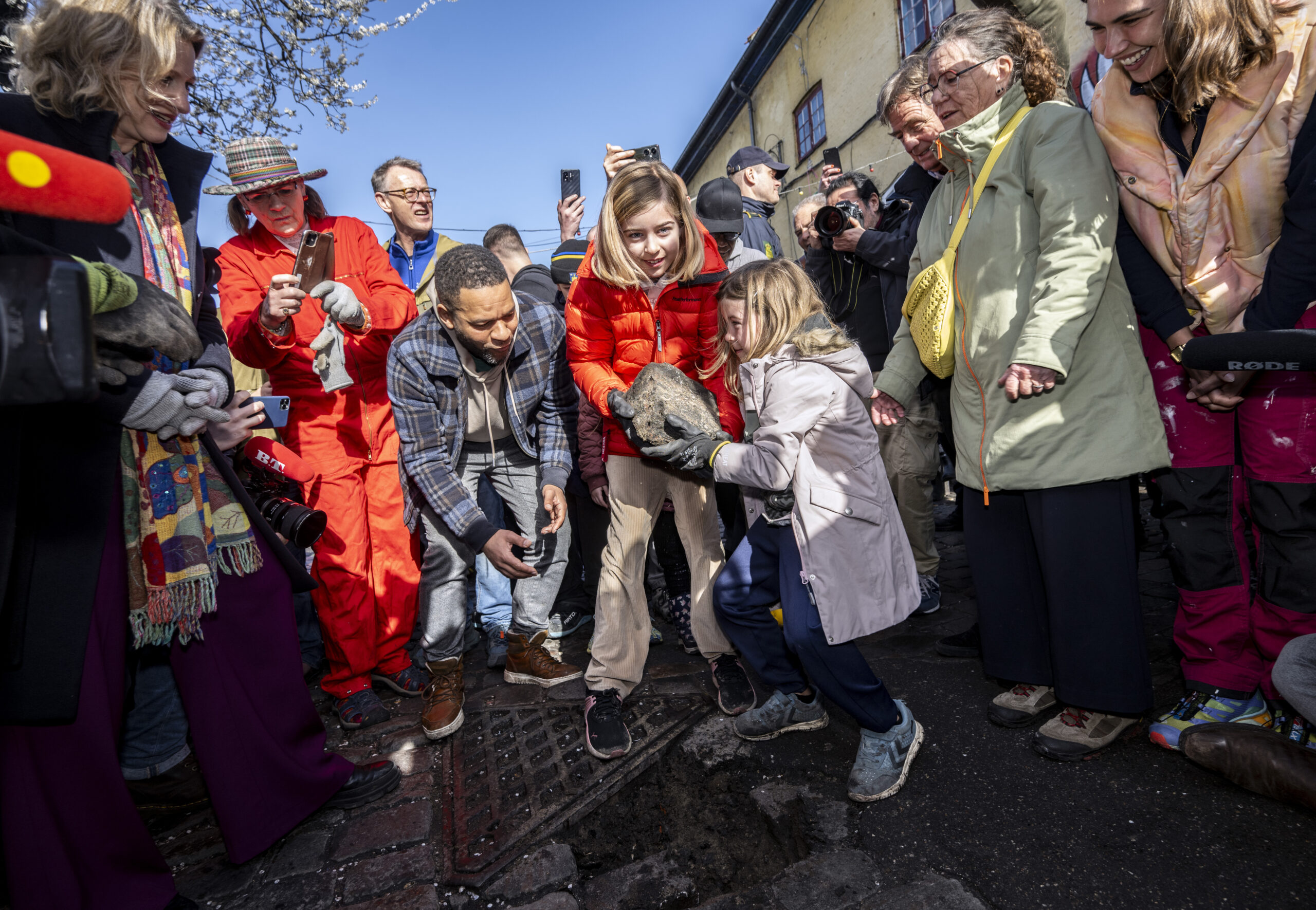 Emilia och Sally, boende i Christiania, tar hand om den första stenen som grävs upp från Pusher Street i Christiania i Köpenhamn på lördagen.(Johan Nilsson/TT).